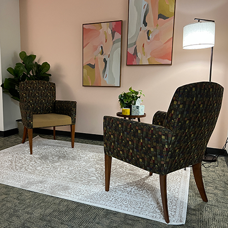 Nice office space with two chairs, a rug, lamp, and art work on the wall.