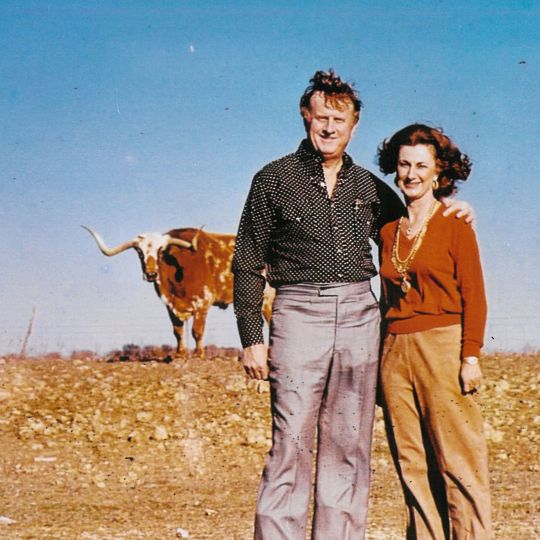 Red McCombs and his wife Charlene pose in front of a longhorn on a ranch