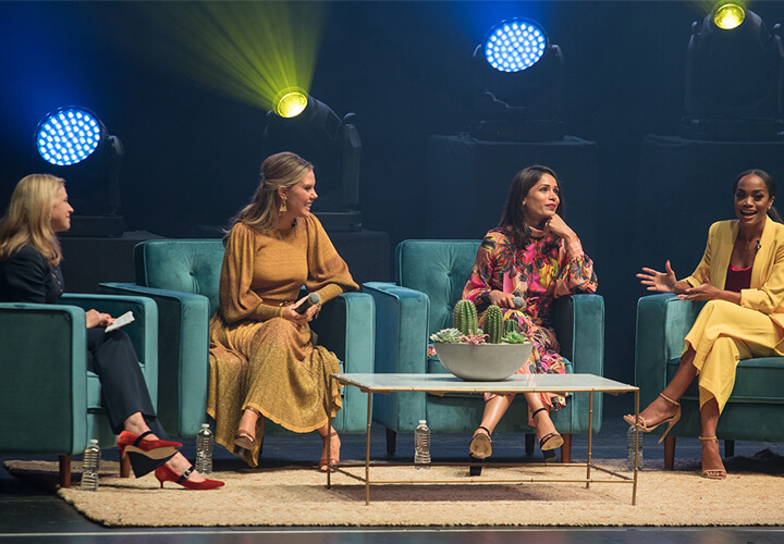 Three panelists speak on couches