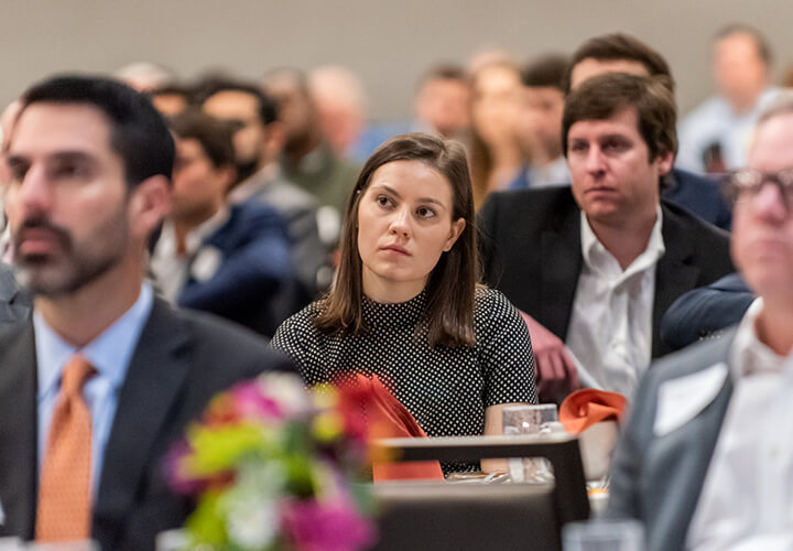 Conference attendees at tables listen attentively