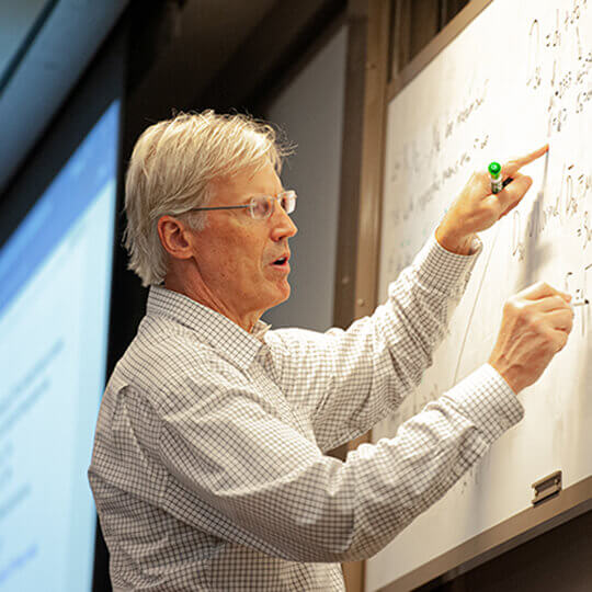 Professor uses a whiteboard while instructing