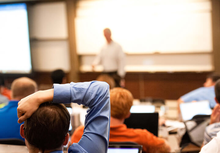 Person with hand on head in lecture hall