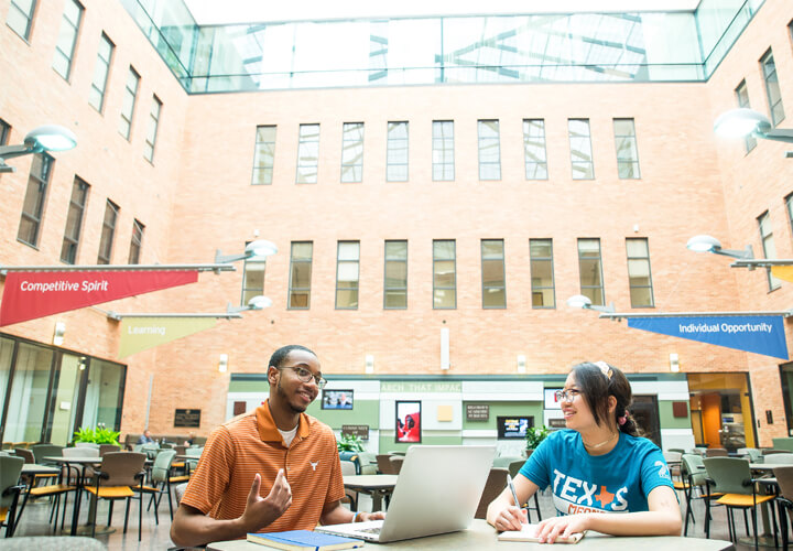 Two students talk in CBA atrium