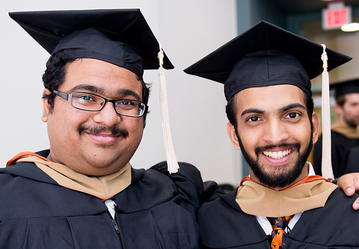 Two MS program graduates in commencement attire