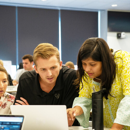 Three students looking at laptop screen together